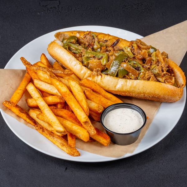 Gardner's Grill cheesesteak sandwich with green peppers and onions, served with seasoned fries and dipping sauce.