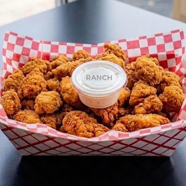 Crispy fried chicken bites in a red and white checkered paper tray with a side of ranch.